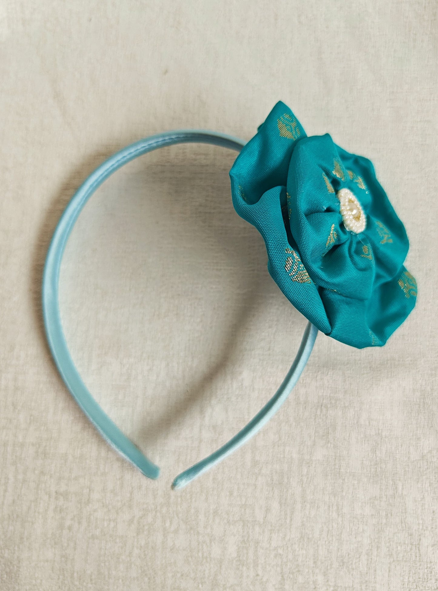 This Aqua Green Big Handcrafted fabric flower headband with pearls embellishment for Girls is expertly crafted with immense love and suitable for girls above the age of 2 years. The intricate handwork and delicate pearl detailing make it a standout accessory for any young girl.