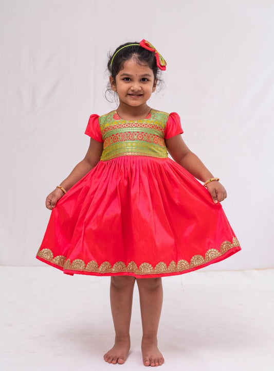 Neon green banaras brocade with candy pink raw silk flared cap sleeved dress for Girls. Elevate any occasion with this unique piece.Let your princess be as comfortable as in her casuals with carefully designed and crafted Comfort Ethnic Wear by Soyara Ethnics. 