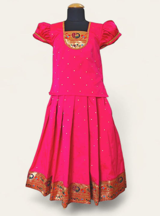 This Fuchsia pink Brocade silk parkar polka boasts an intricate Paithani border and yoke pattern, designed specifically for girls. The addition of puff sleeves accented with golden lace adds a touch of elegance to the garment.