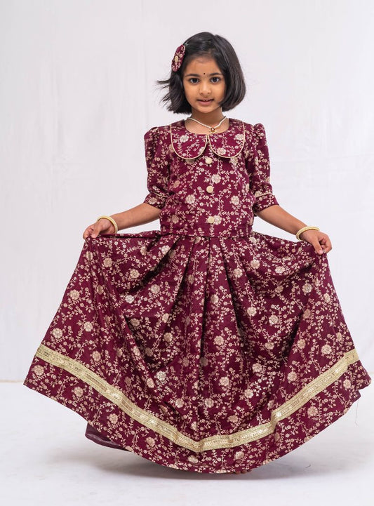 This Dark Plum banaras brocade ghagra is complemented by a Peterpan collared mutton sleeved choli.Let your princess be as comfortable as in her casuals with carefully designed & crafted Comfort Ethnic Wear by Soyara Ethnics.Keep her fashion quotient high with timeless patterns, vibrant combinations and royal textiles.