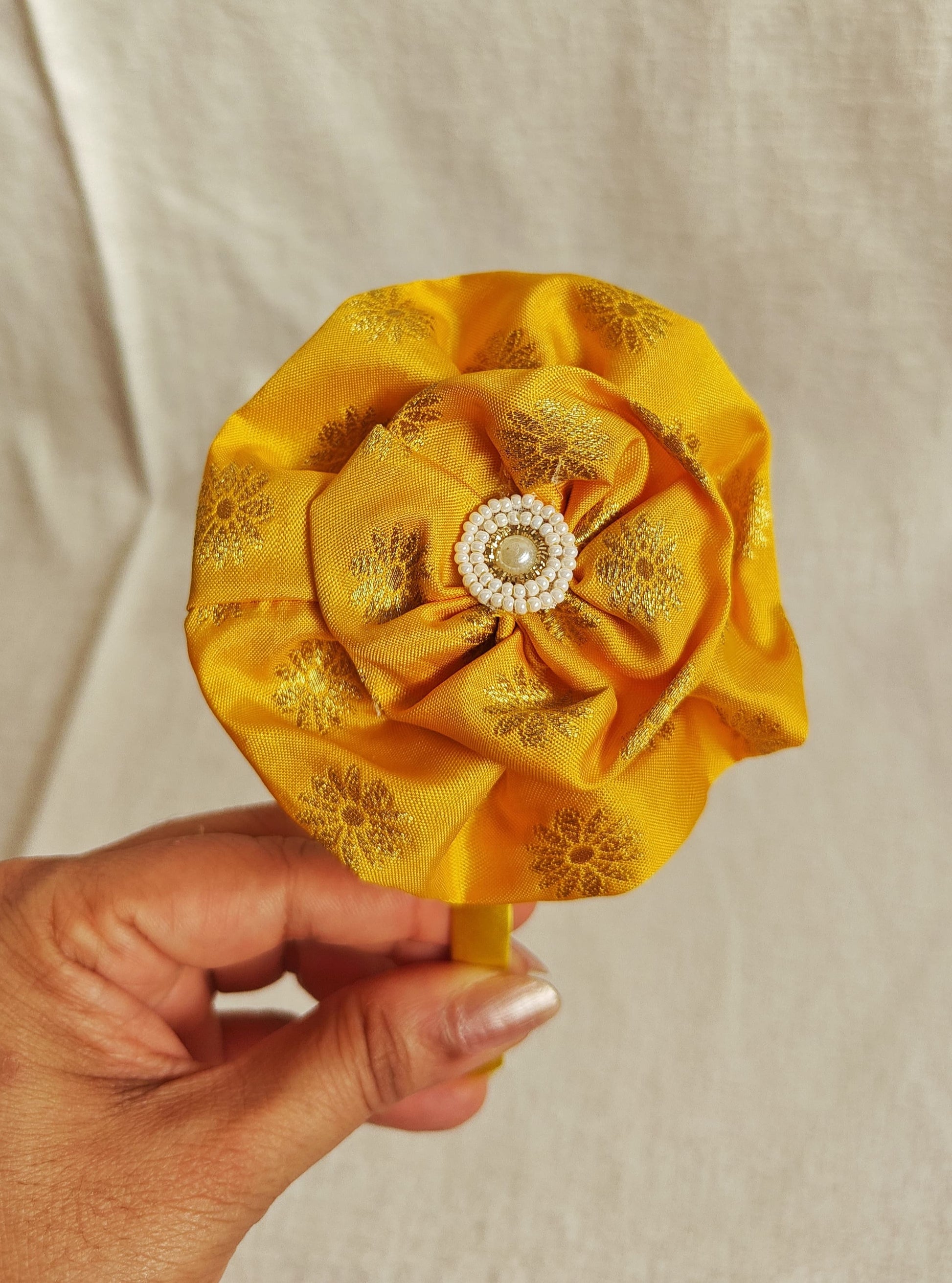 This Yellow Big Handcrafted fabric flower headband with pearls embellishment for Girls is expertly crafted with immense love and suitable for girls above the age of 2 years. The intricate handwork and delicate pearl detailing make it a standout accessory for any young girl.