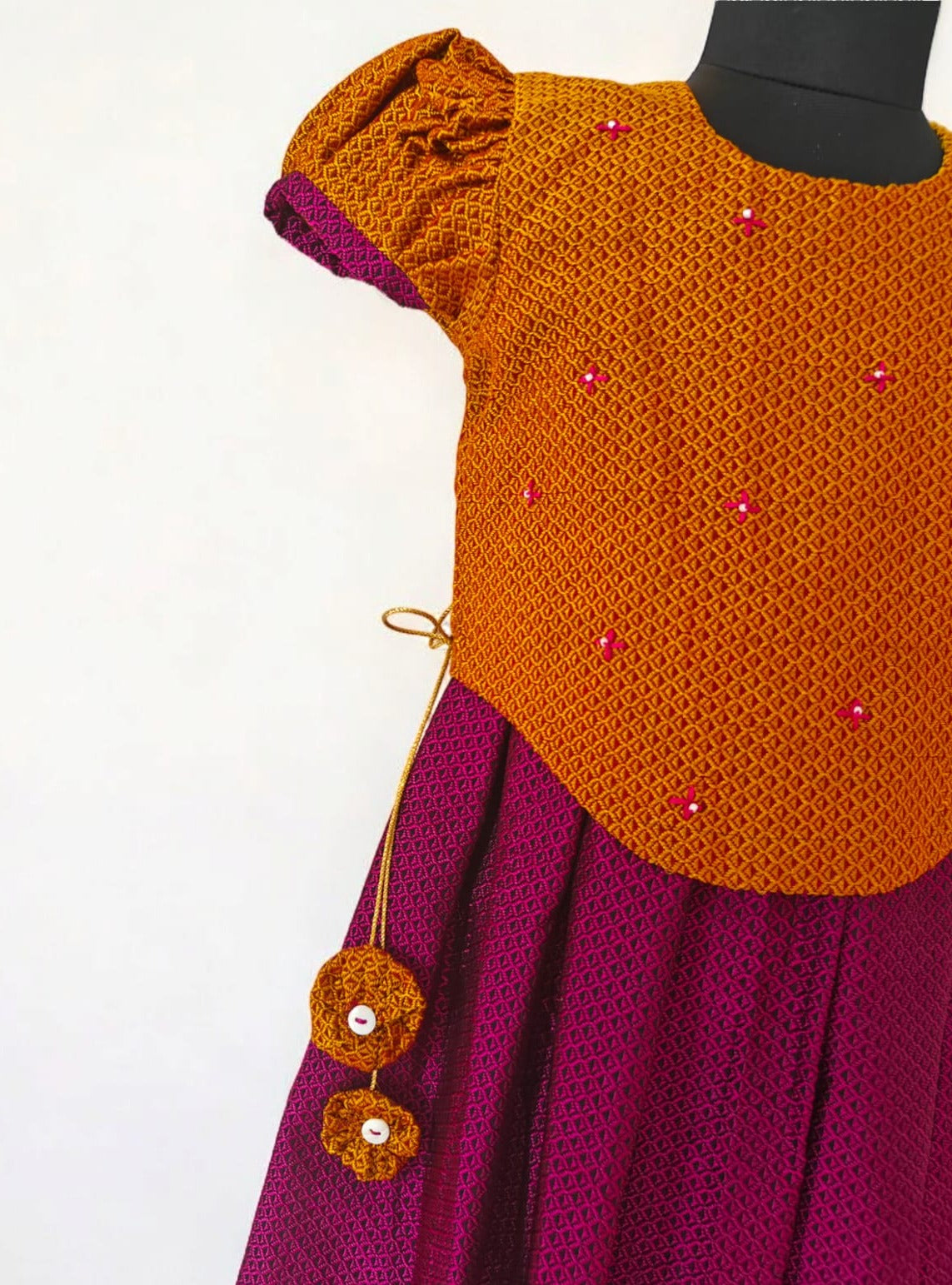 Magenta Khunn Dress with Contrast Turmeric Yellow hand embroidered blouse with cute puff sleeves. Apple cut blouse has cute flower latkans on both sides that dangle while walking. Also Unique Patti border of khunn is something not to miss for Khunn lovers