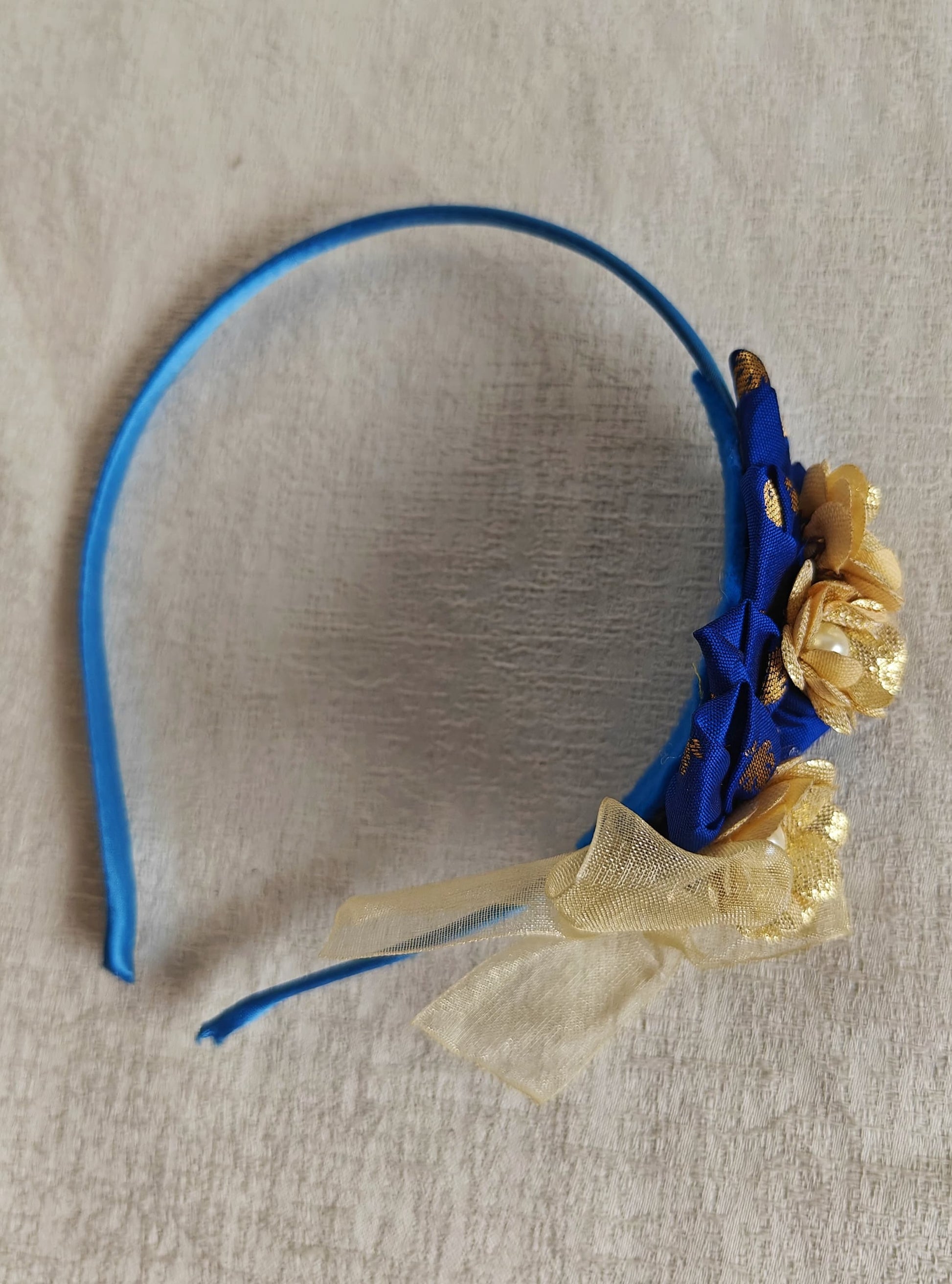 This Royal blue headband for girls features delicate fabric flowers and is handcrafted with great care. It is ideal for girls over the age of 2 and makes a lovely addition to any outfit.