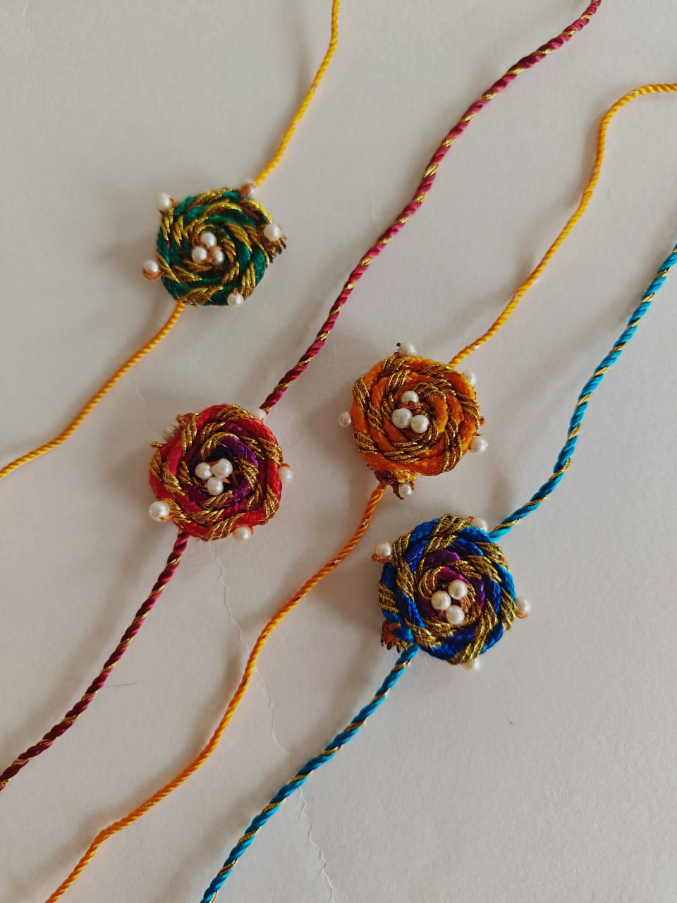 Set of 4 Spiralled fabric chord rakhis with pearls embellishments. Suitable for all ages.