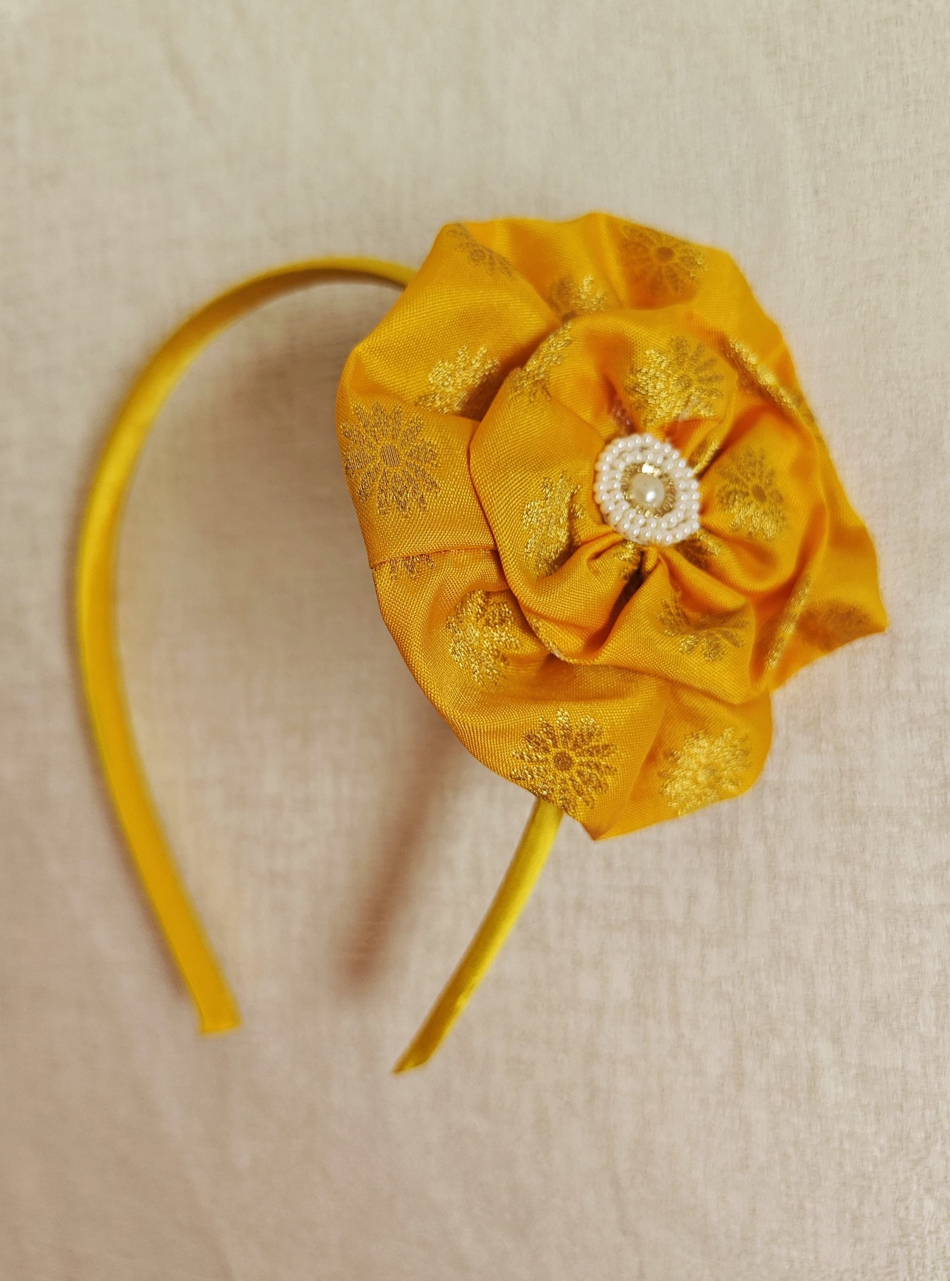 This Yellow Big Handcrafted fabric flower headband with pearls embellishment for Girls is expertly crafted with immense love and suitable for girls above the age of 2 years. The intricate handwork and delicate pearl detailing make it a standout accessory for any young girl.