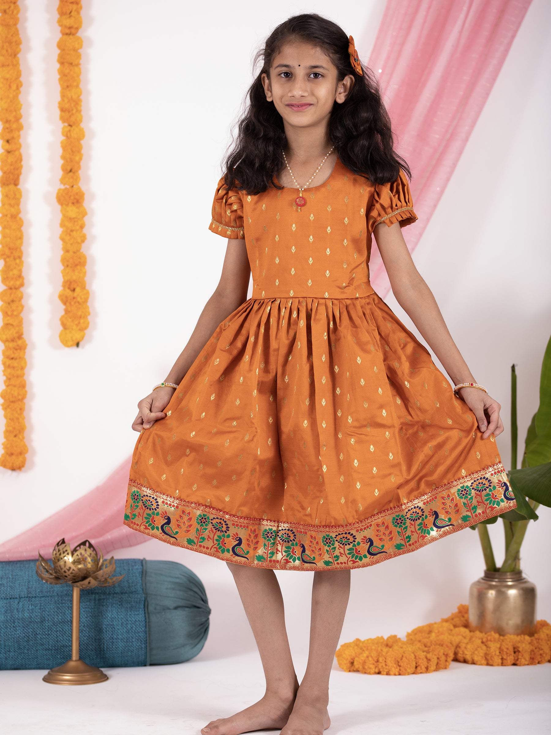 Rust colored taffeta silk frock with intricate peacock paithani border for Girl.Let your princess be as comfortable as in her casuals with carefully designed & crafted Comfort Ethnic Wear by Soyara Ethnics.Keep her fashion quotient high with timeless patterns, vibrant combinations and royal textiles.