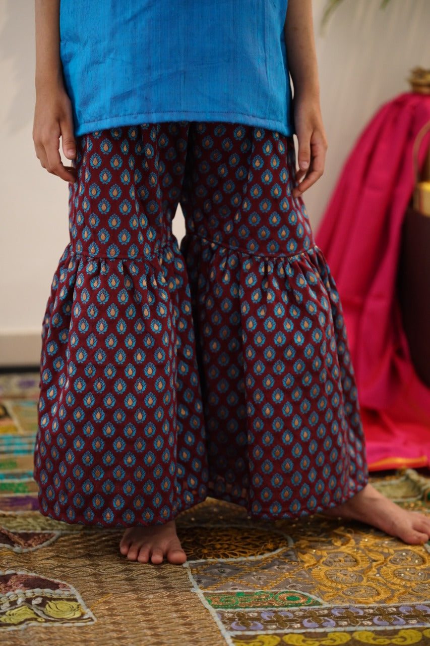 Brocade chanderi coffee brown sharara pants with peacock blue pure raw silk tunic.Let your princess be as comfortable as in her casuals with carefully designed & crafted Comfort Ethnic Wear by Soyara Ethnics.Keep her fashion quotient high with timeless patterns, vibrant combinations and royal textiles.